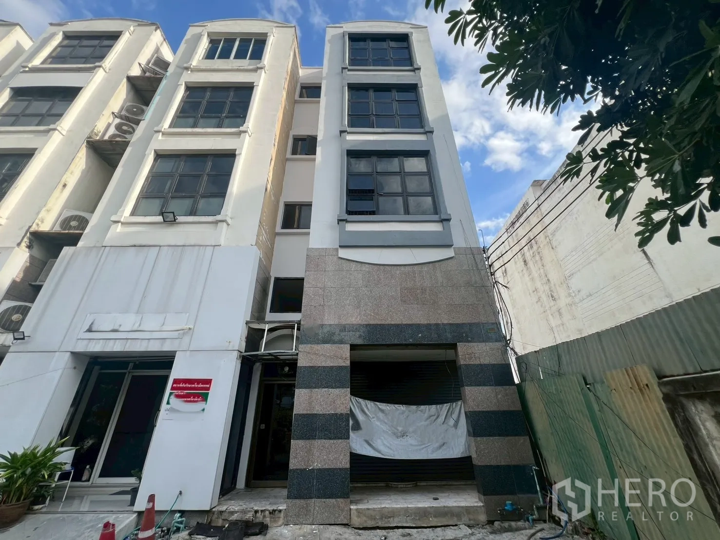 Shophouse for rent in Phra Khanong, Bangkok - Four-storey shophouse facade with wide windows and roller shutter entrance.