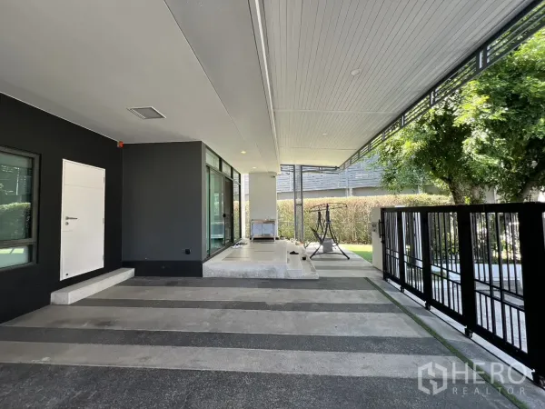 Detached House for sale in Bang Kapi, Bangkok - Carport beside floor-to-ceiling windows and black metal gate to the garden.