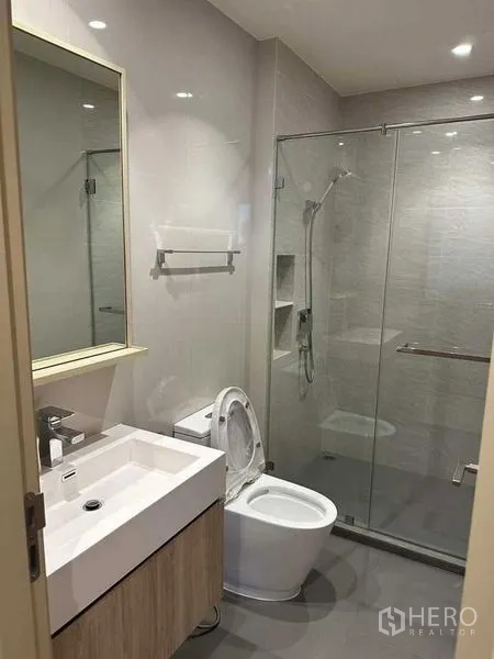 公寓 出租在Watthana, Bangkok - 现代浴室，玻璃淋浴房、洗手台与坐便器。
