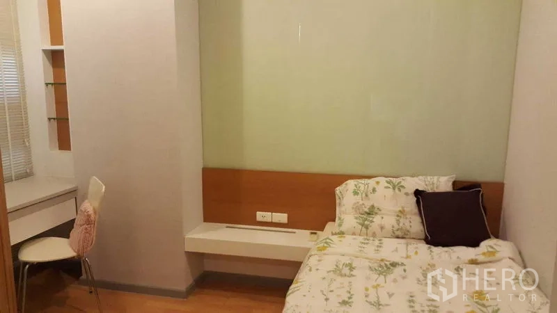 Condominium for rent in Khlong Toei, Bangkok - Cozy second bedroom with single bed, built-in desk, shelving and wood flooring.