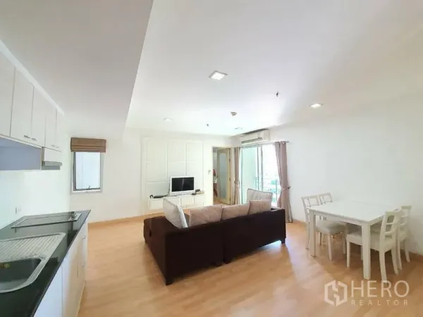 Condominium for rent in Din Daeng, Bangkok - Open-plan living area with kitchenette, dining table, sofa, TV console, and balcony doors.