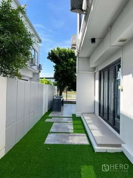 独立式住宅 出租或出售在Bang Phli, Samut Prakan - 侧院铺设人造草与踏步石，配高隐私围墙。