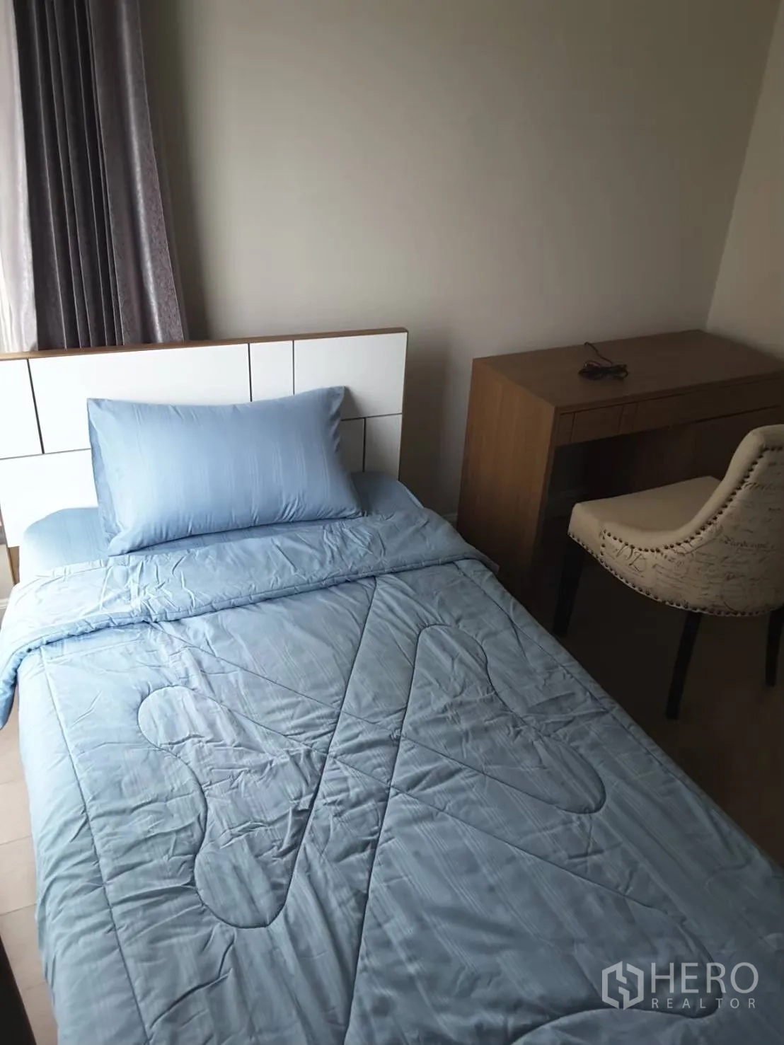Condominium for rent in Khlong Toei, Bangkok - Second bedroom with a single bed in blue bedding and a study desk by the window.