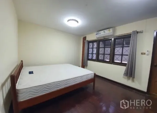 联排别墅 出租在Watthana, Bangkok - 卧室带木地板，大窗与空调。