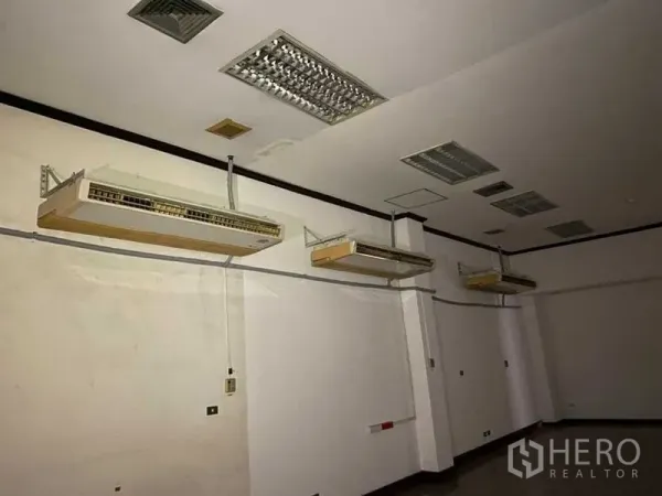 Retail Space for rent - Interior room with multiple wall‑mounted air conditioners and fluorescent ceiling lights.