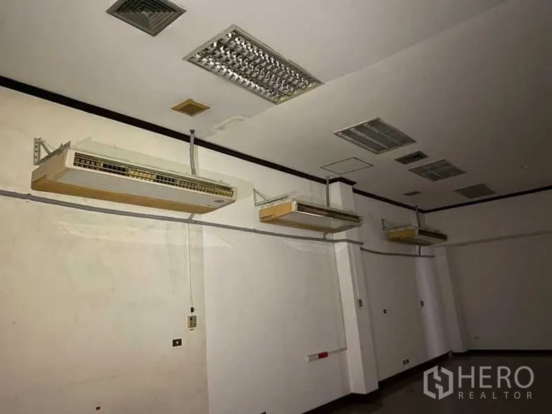 Retail Space for rent - Interior room with multiple wall‑mounted air conditioners and fluorescent ceiling lights.
