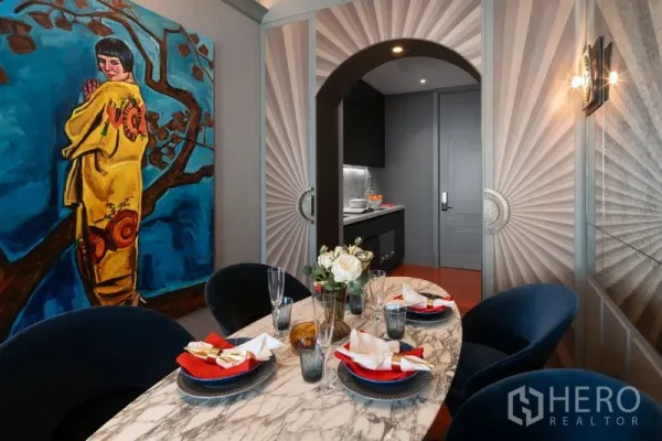 คอนโด ขายในWatthana, Bangkok - โต๊ะอาหารหินอ่อนจัดเซ็ตข้างภาพศิลปะสีสันสด และซุ้มโค้งสู่ครัว