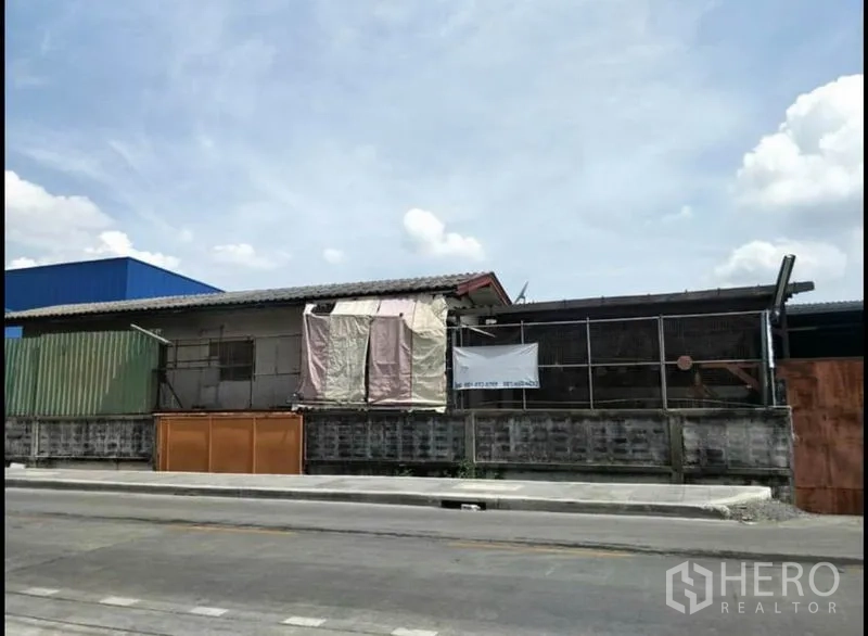 货栈 出售在Lat Krabang, Bangkok - 仓库侧立面，矮墙与波纹金属板围护。