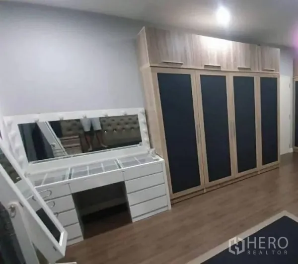 独立式住宅 出售在Pathum Thani - 卧室一角，整面落地衣柜与带镜化妆台。