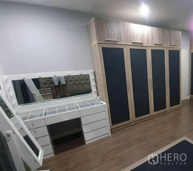 独立式住宅 出售在Pathum Thani - 卧室一角，整面落地衣柜与带镜化妆台。