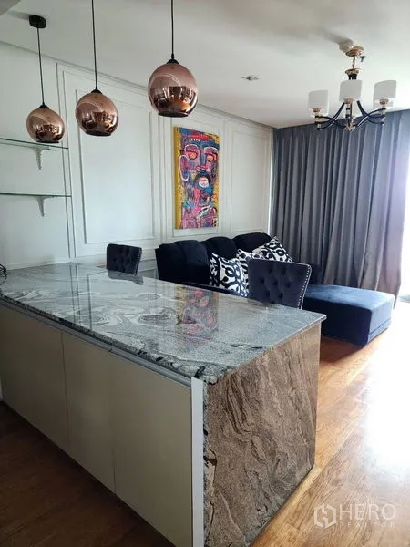 Condominium for rent in Bang Rak, Bangkok - Marble breakfast bar with copper pendant lamps facing a cozy lounge with sofa and full curtains.