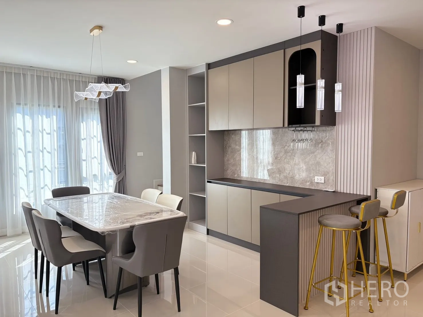 บ้าน for rent in Bang Phli, Samut Prakan - มุมทานอาหารโต๊ะหินอ่อน 6 ที่นั่ง โคมแขวน และแพนทรีสไตล์โมเดิร์นพร้อมบาร์และที่แขวนแก้วไวน์.