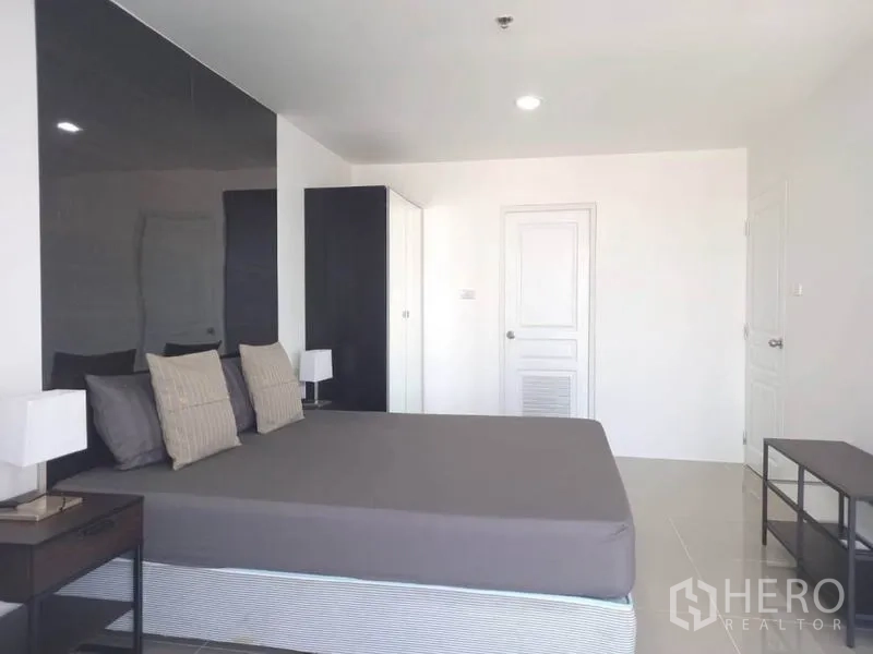 Condominium for rent in Khlong Toei, Bangkok - Large bedroom in neutral tones with bedside lamps and ample storage.