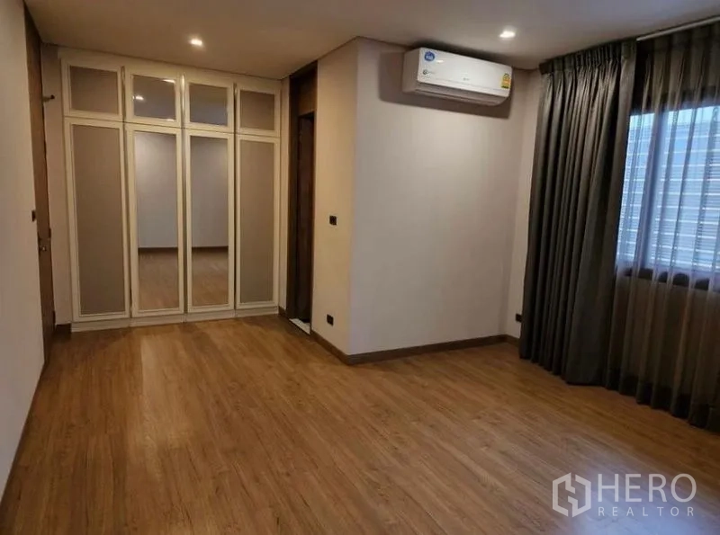 Townhouse for sale in Yan Nawa, Bangkok - Bright bedroom with built-in wardrobe, wood floors and window drapes.