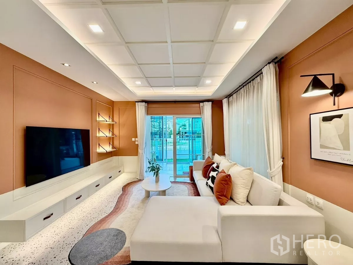 บ้าน ให้เช่าในBang Phli, Samut Prakan - มุมมองกลับของห้องนั่งเล่นพร้อมผนังทีวีและผ้าม่านโปร่ง