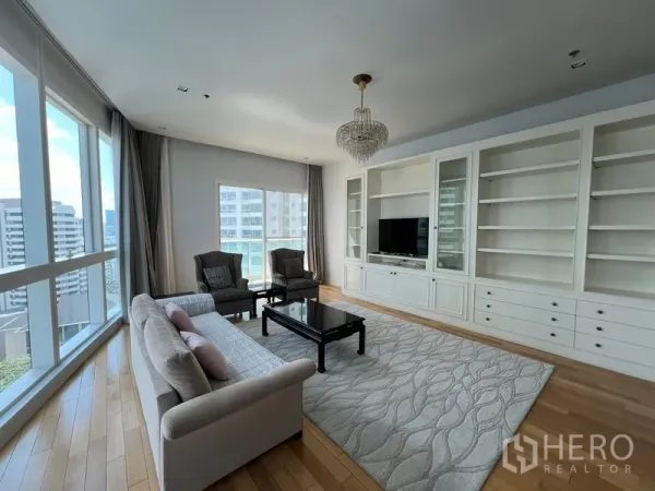Condominium for rent in Khlong Toei, Bangkok - Spacious lounge with wall-to-wall cabinetry, large rug and panoramic corner windows.