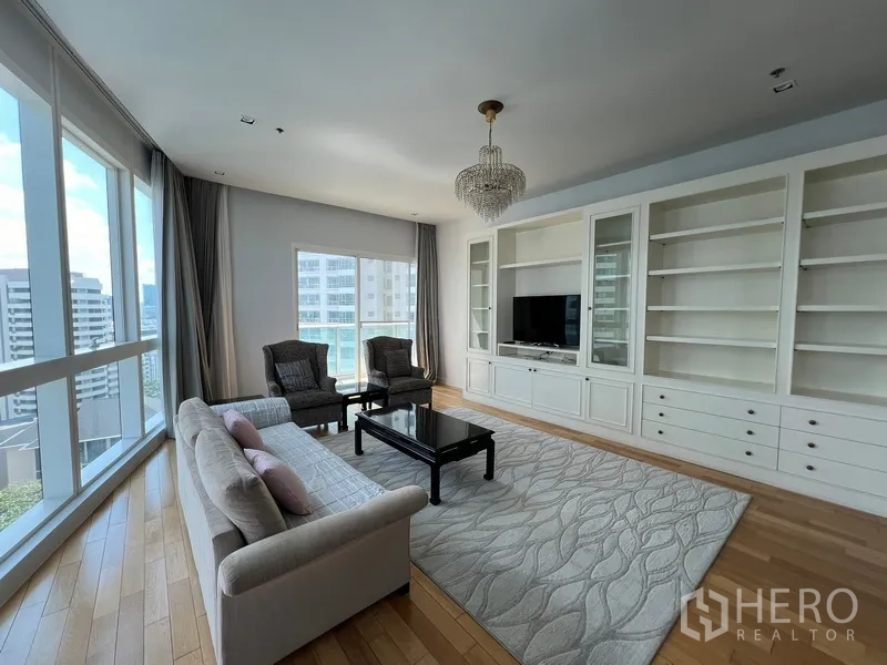 Condominium for rent in Khlong Toei, Bangkok - Spacious lounge with wall-to-wall cabinetry, large rug and panoramic corner windows.