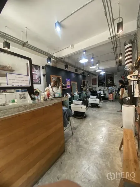 店屋 出租或出售在Khlong Toei, Bangkok - 一层理发店式商业空间，接待台、理发椅与吊灯，水泥地面。