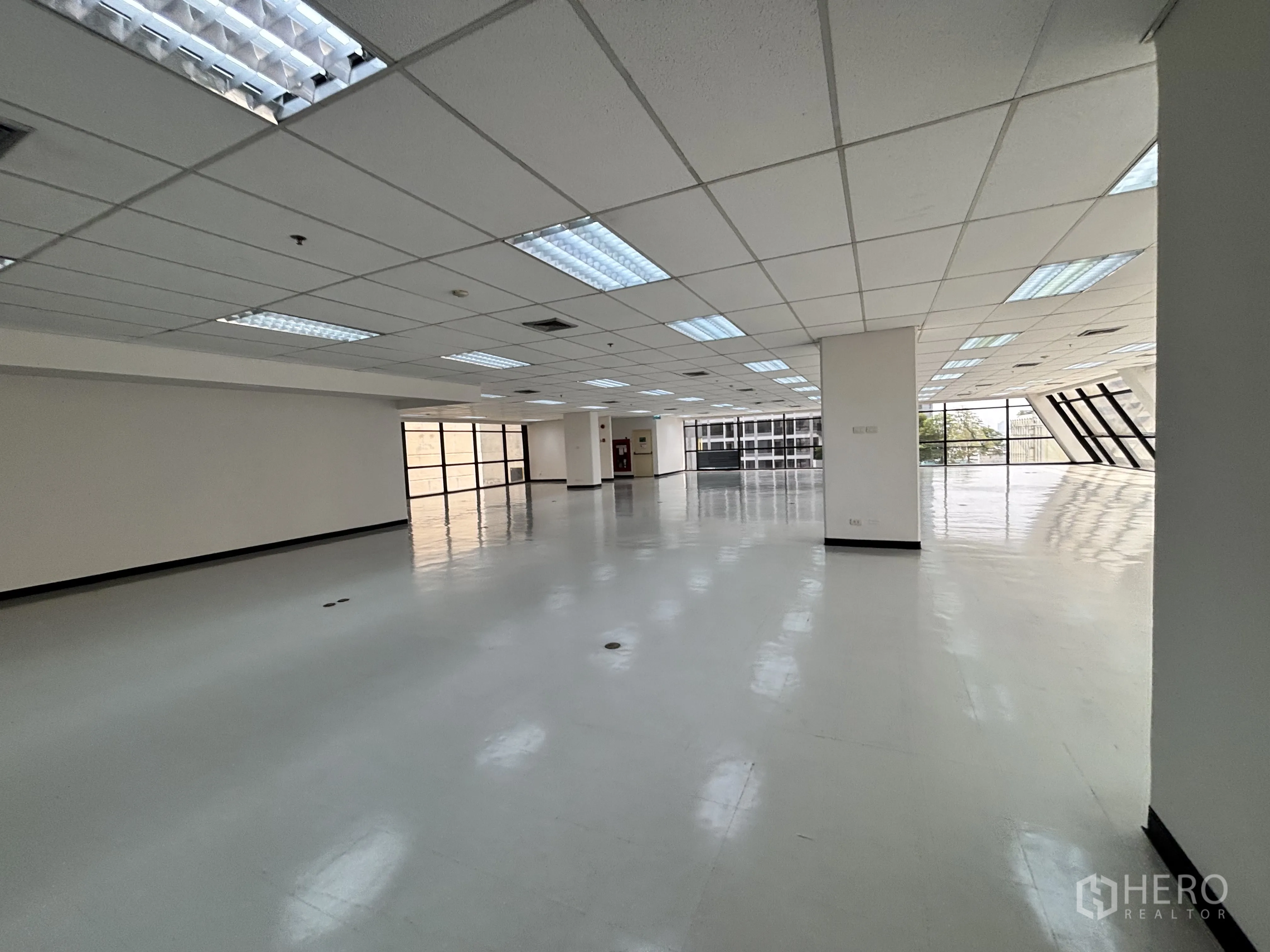 ออฟฟิศ for rent in Ratchathewi, Bangkok - โถงทำงานโล่ง มีเสาโครงสร้าง พื้นสีเทาอ่อน และหน้าต่างสองด้านรับแสงธรรมชาติ.