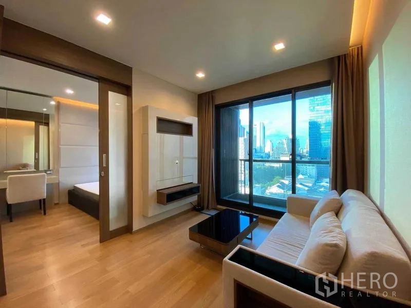 Condominium for rent in Bang Rak, Bangkok - Living area with large glass doors to balcony and a separate bedroom.