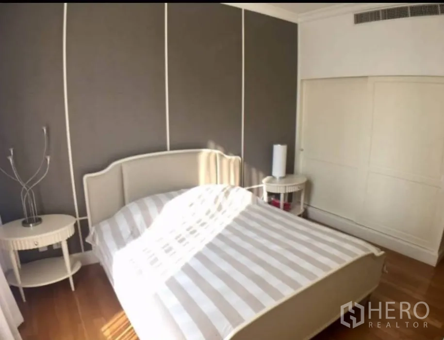 Condominium for rent in Watthana, Bangkok - Sunlit master bedroom with striped bedding, grey feature wall and built-in wardrobe.