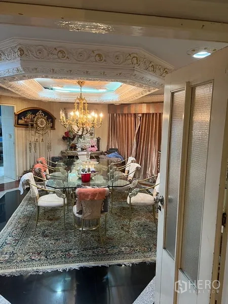 Condominium for sale in Khlong Toei, Bangkok - Large dining space with elongated glass-top table, ornate chandelier and area rug.
