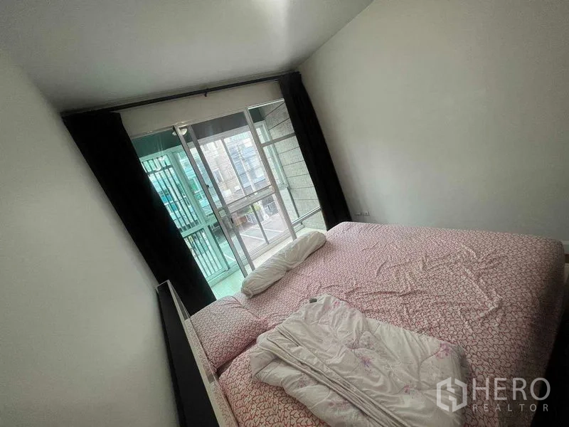 Townhouse for rent in Bueng Kum, Bangkok - Bedroom with balcony access through sliding glass door and curtains.