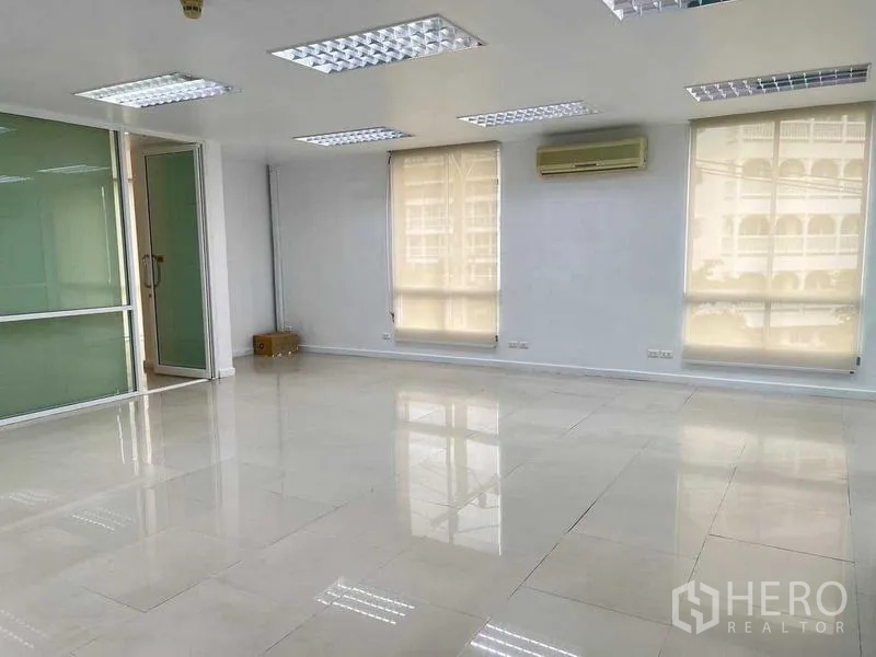 Office Space for rent in Wang Thonglang, Bangkok - Large office hall with multiple windows, wall AC unit, and glossy ceramic tile flooring.