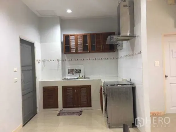 带办公室的家 出租在Wang Thonglang, Bangkok - 王通朗区家庭办公楼的厨房，木质橱柜、白色墙砖与不锈钢油烟机。
