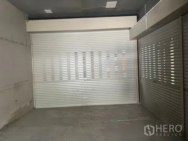 Retail Space for rent in Khlong Toei, Bangkok - Empty retail space featuring dual metal roller shutters and unfinished concrete flooring.