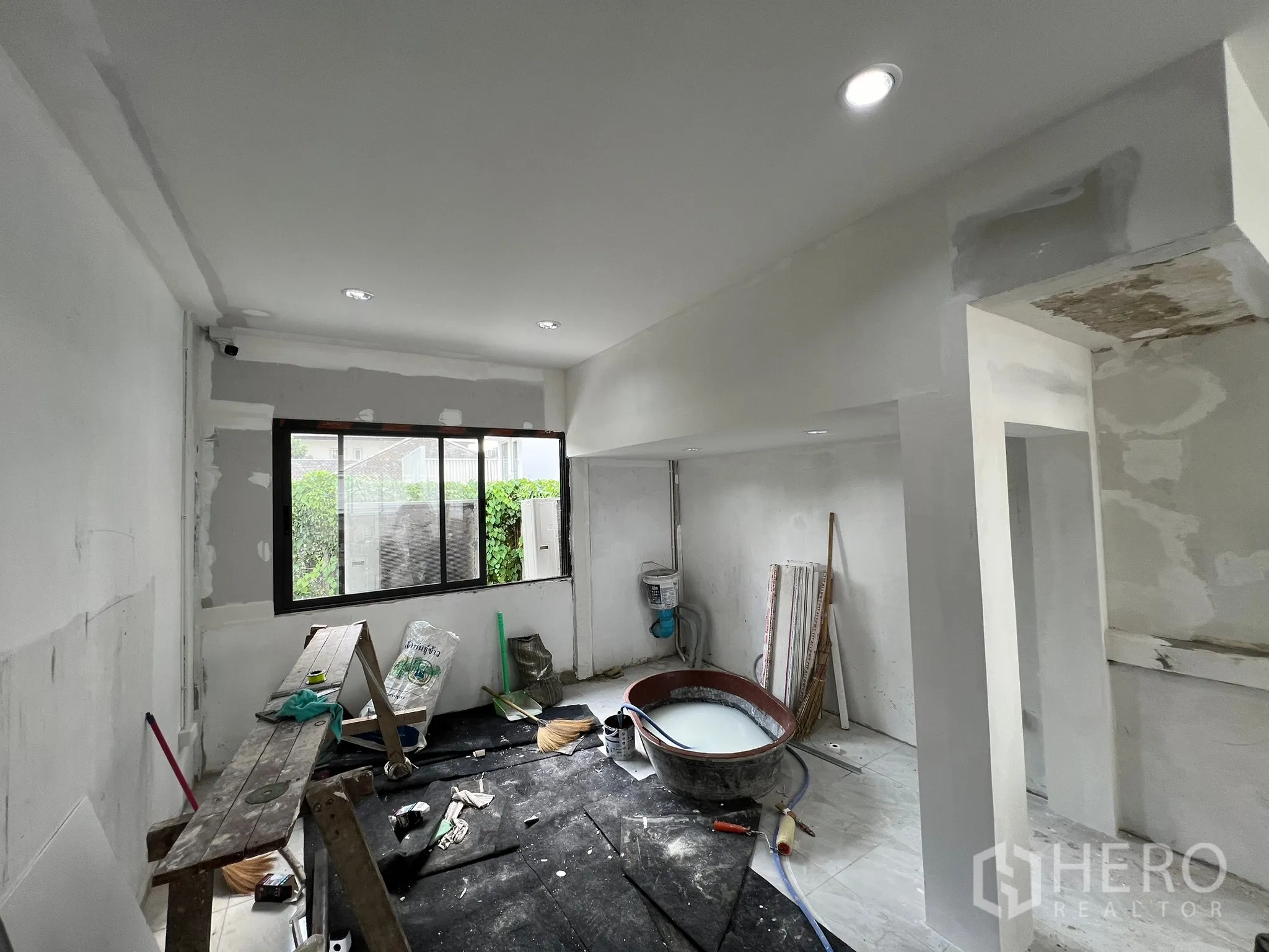 Retail Space for rent in Khlong Toei, Bangkok - Ground floor under renovation showing tools, unfinished walls and a window to greenery.