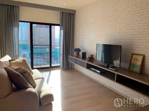Condominium for rent in Phaya Thai, Bangkok - Bright living room with sofa, TV console and sliding doors opening to a balcony with city view.