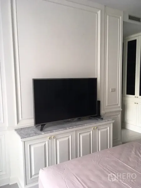 Condominium for rent in Pathum Wan, Bangkok - Bedroom media wall featuring a flat-screen TV on a marble-topped cabinet with built-in storage.