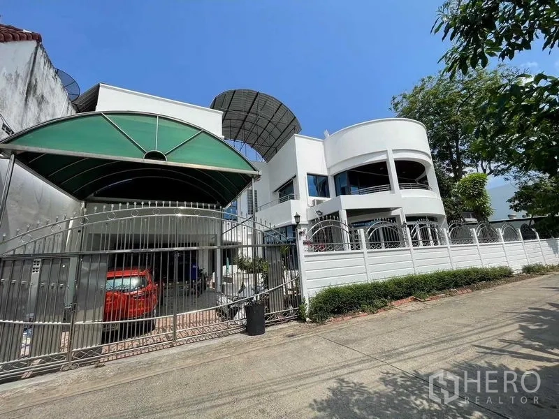 带办公室的家 出售 - 正立面可见宽大大门、带顶车位与拱形车棚。