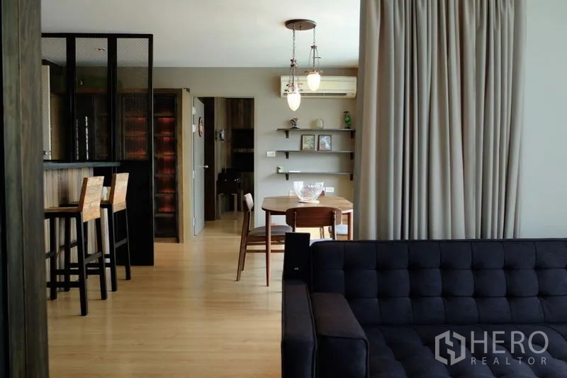Condominium for sale in Watthana, Bangkok - Spacious living and dining area with sofa, shelves and bar counter in an industrial modern style.
