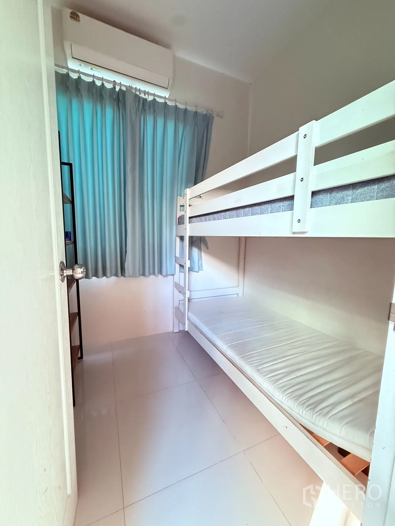 Detached House for rent or sale in Prawet, Bangkok - Compact room with white bunk bed, tile floor, curtains, and wall-mounted air conditioner.