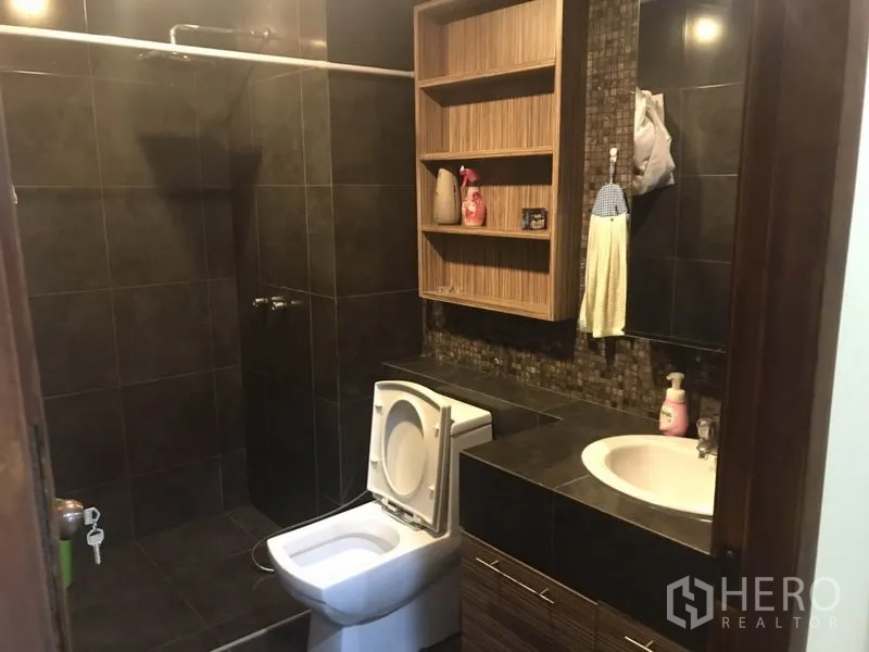 Condominium for rent in Watthana, Bangkok - Bathroom with dark tiles, walk-in shower and built-in shelving.