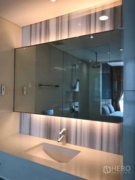 Condominium for rent in Watthana, Bangkok - Sleek bathroom vanity with wide backlit mirror and single basin.
