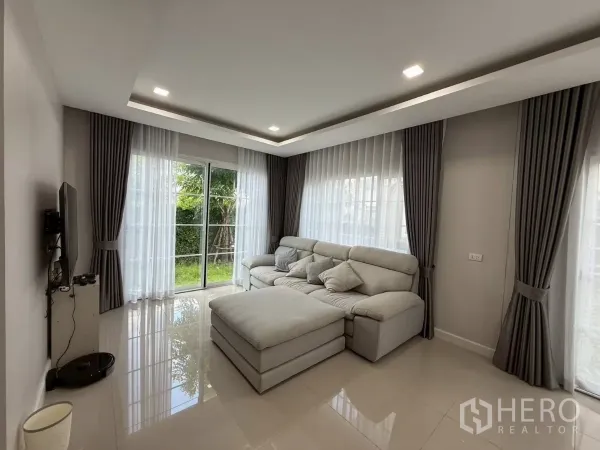 Detached House for rent in Bang Phli, Samut Prakan - Living room with sheer curtains and sliding glass doors opening to the garden.
