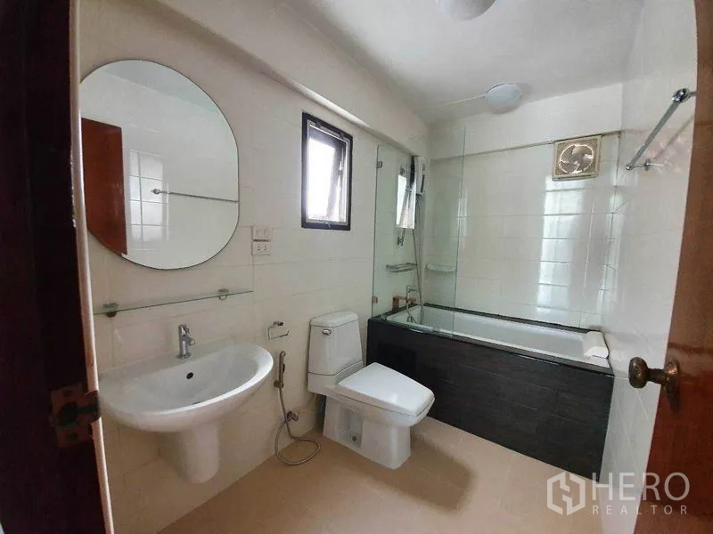 Detached House for rent in Phra Khanong, Bangkok - Clean bathroom with bathtub, glass screen, window and white sanitary ware.