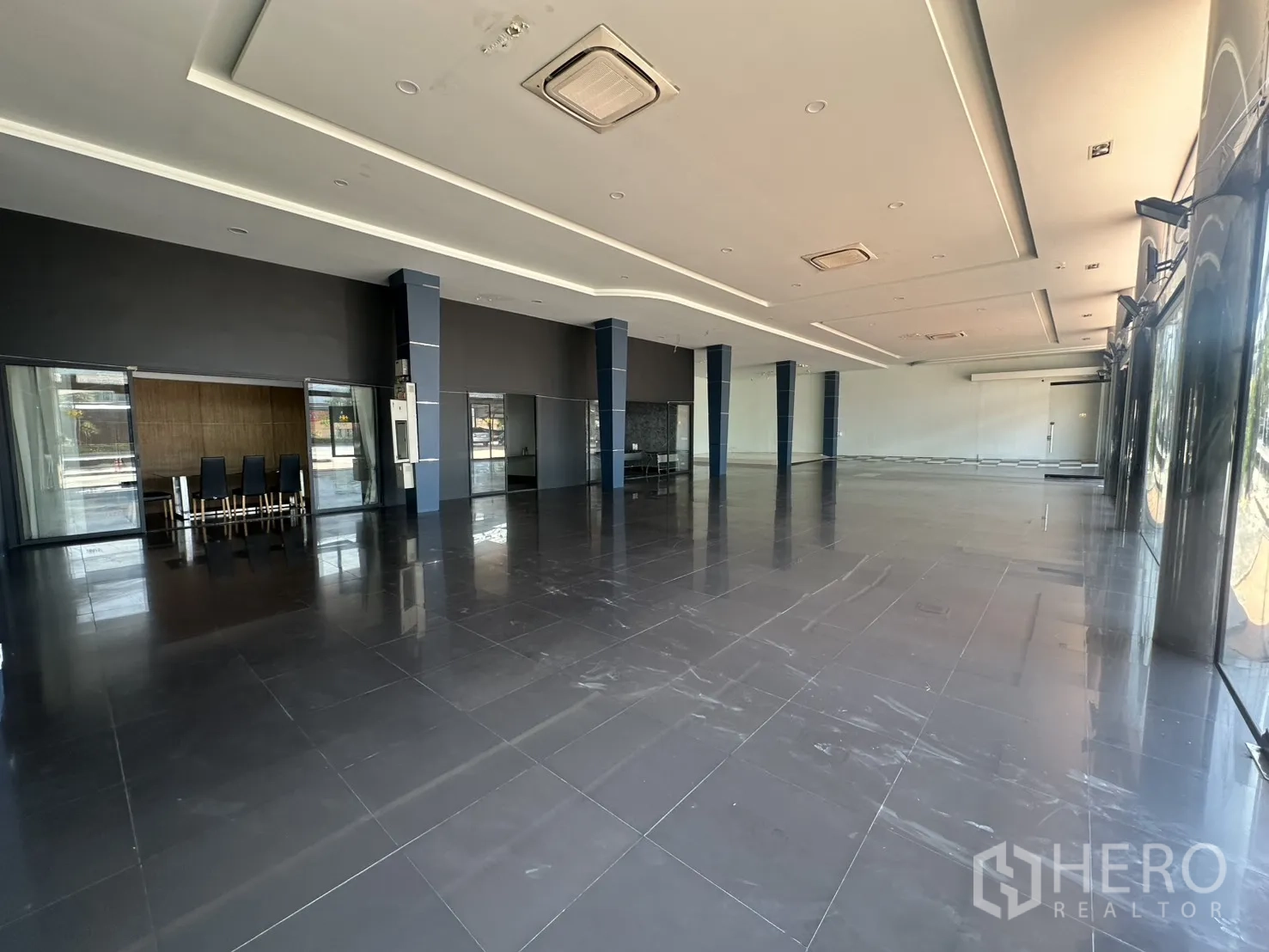 Showroom for rent in Suan Luang, Bangkok - Expansive open-plan showroom with glossy tiles, high ceiling, and columns.