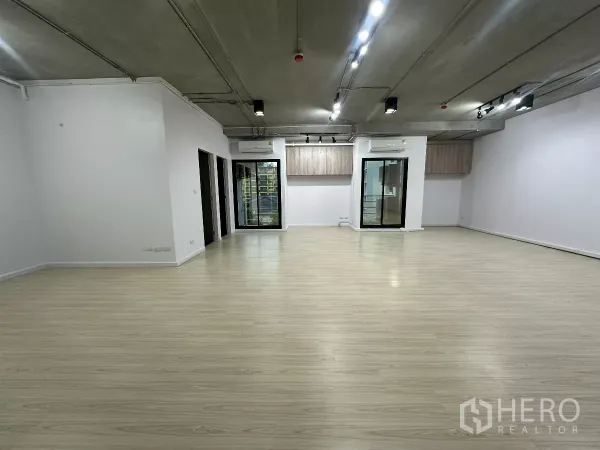 办公空间 出租在Watthana, Bangkok - 宽敞办公大厅，成排聚光灯，两扇玻璃门，浅木地板与白墙。