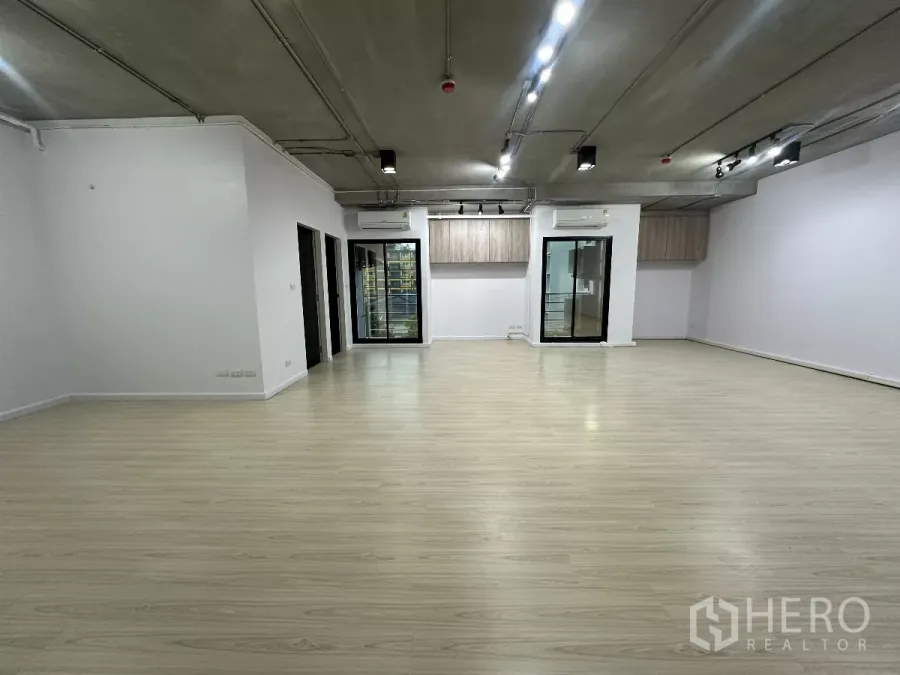 办公空间 出租在Watthana, Bangkok - 宽敞办公大厅，成排聚光灯，两扇玻璃门，浅木地板与白墙。