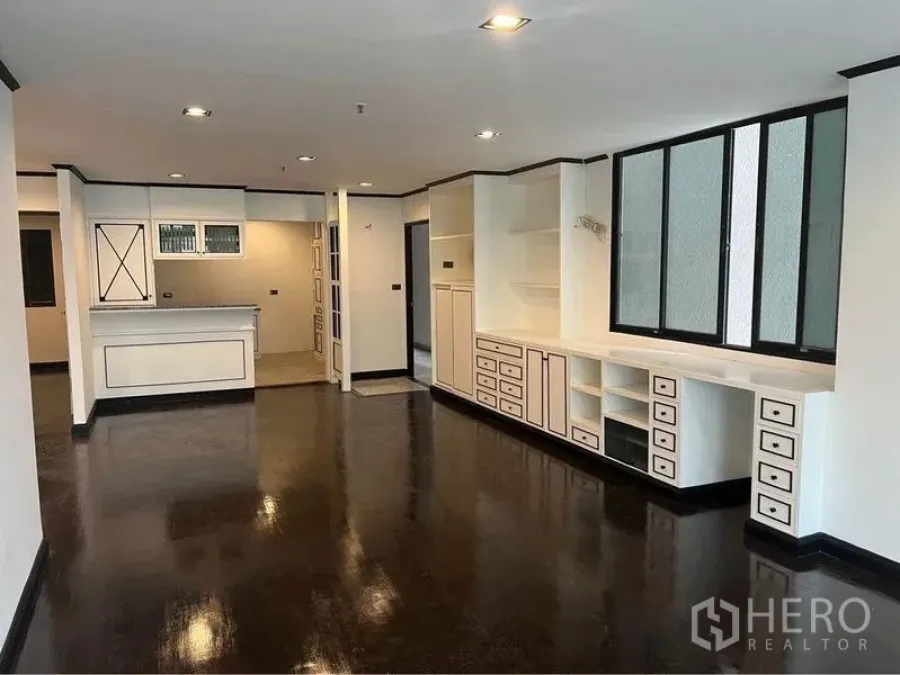 Condominium for rent or sale in Watthana, Bangkok - Open living–dining zone with long built-in media wall and view to kitchen.