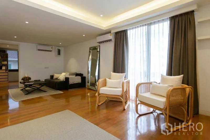 Home Office for sale in Watthana, Bangkok - Bright lounge space with seating, large window and recessed ceiling lights on wood flooring.