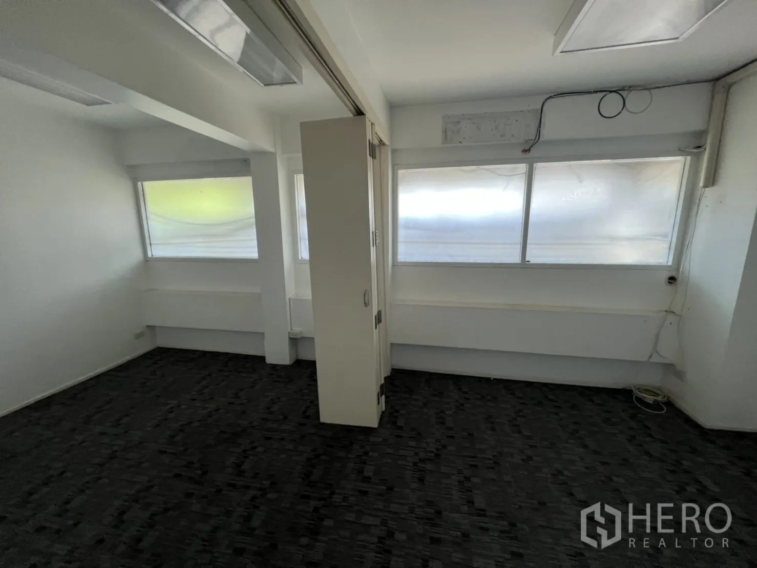 Shophouse for rent or sale in Watthana, Bangkok - Small partitioned office with carpet tiles and a sliding divider.