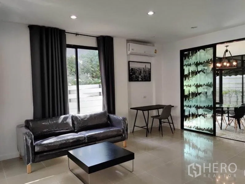 Townhouse for rent in Suan Luang, Bangkok - Lounge with sofa and work desk overlooking the garden dining space.