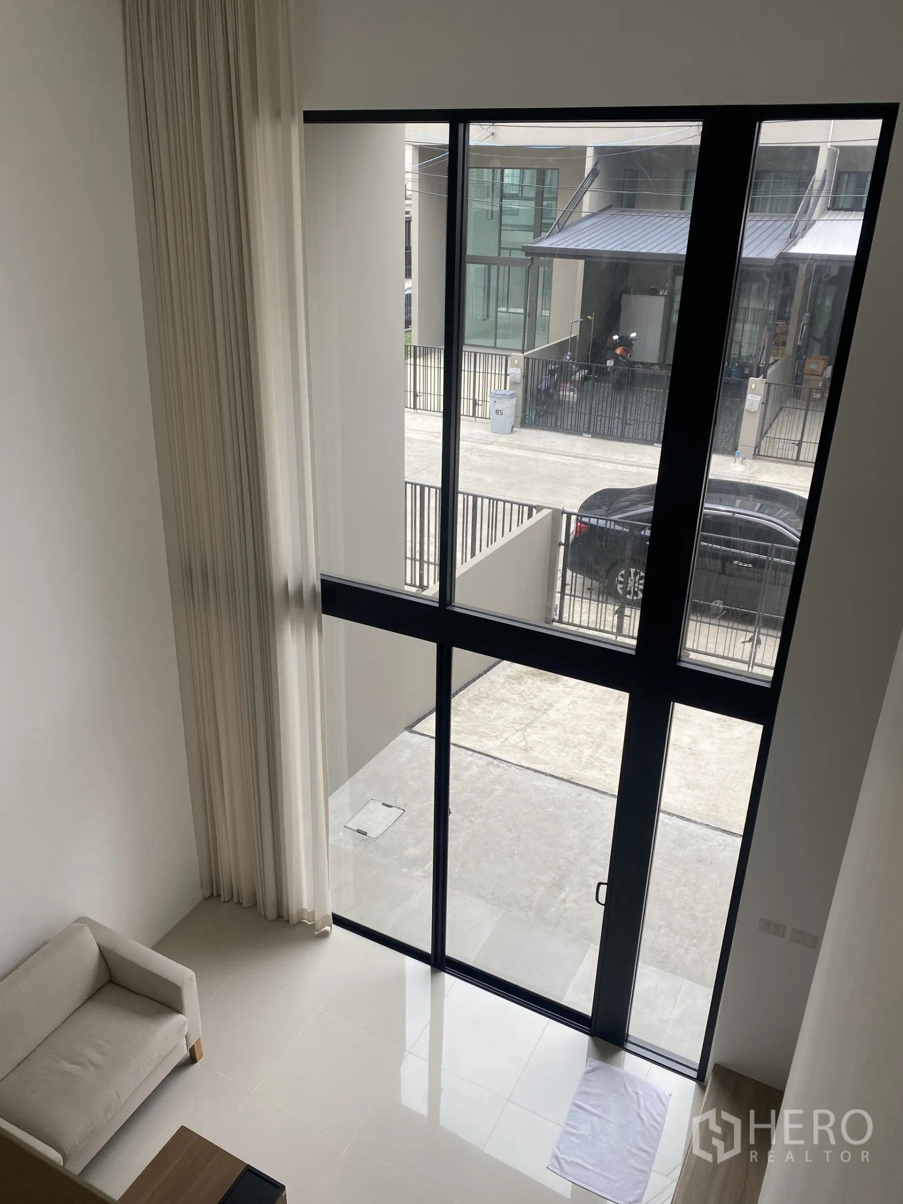 联排别墅 出租或出售在Bang Khae, Bangkok - 从夹层俯瞰客厅，看到通向前庭的高大推拉落地门