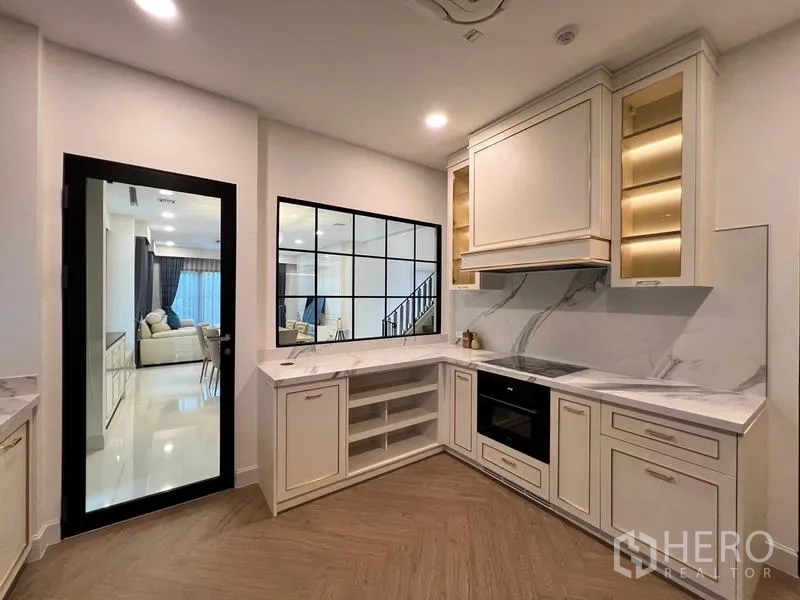 Detached House for rent or sale in Saphan Sung, Bangkok - U-shaped kitchen with marble countertops, built-in oven and glass partition.