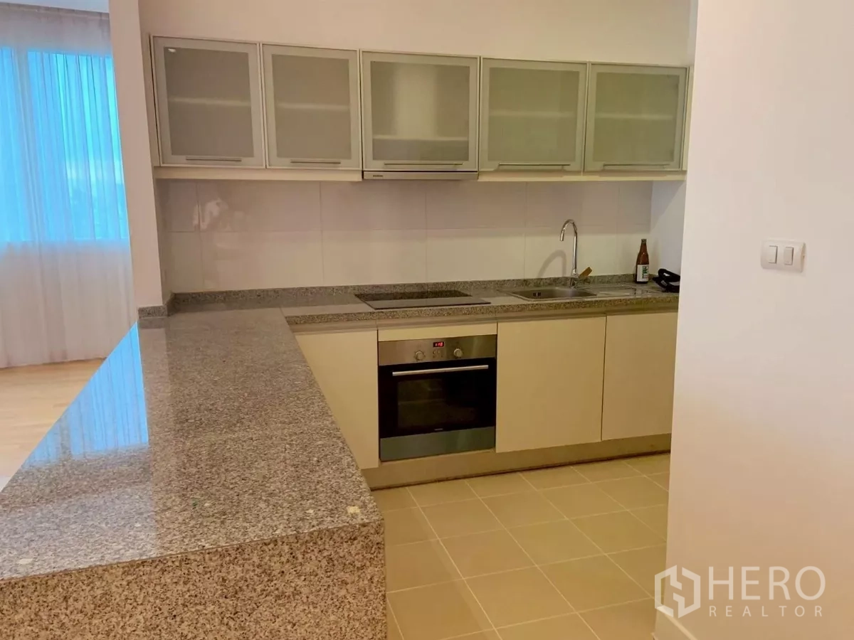 Condominium for rent in Khlong Toei, Bangkok - Open kitchen with granite countertop, oven and cabinets.